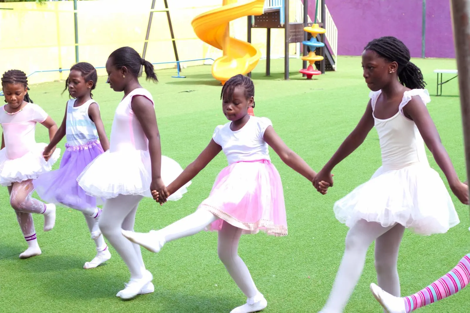 Young ballet dancers holding hands during an outdoor performance
