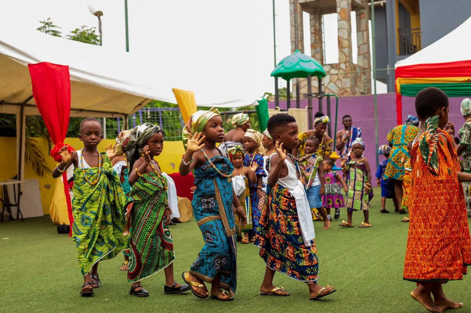 A group of pupils in traditional dress dancing beside the school building