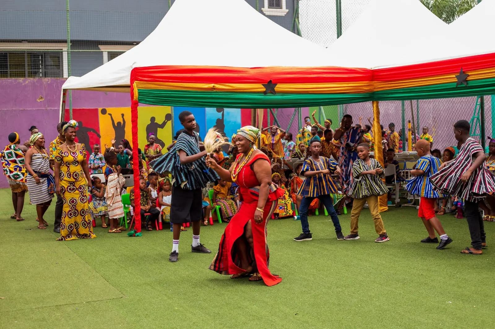 A group of HABIS pupils dancing in traditional clothing beside a decorated canopy