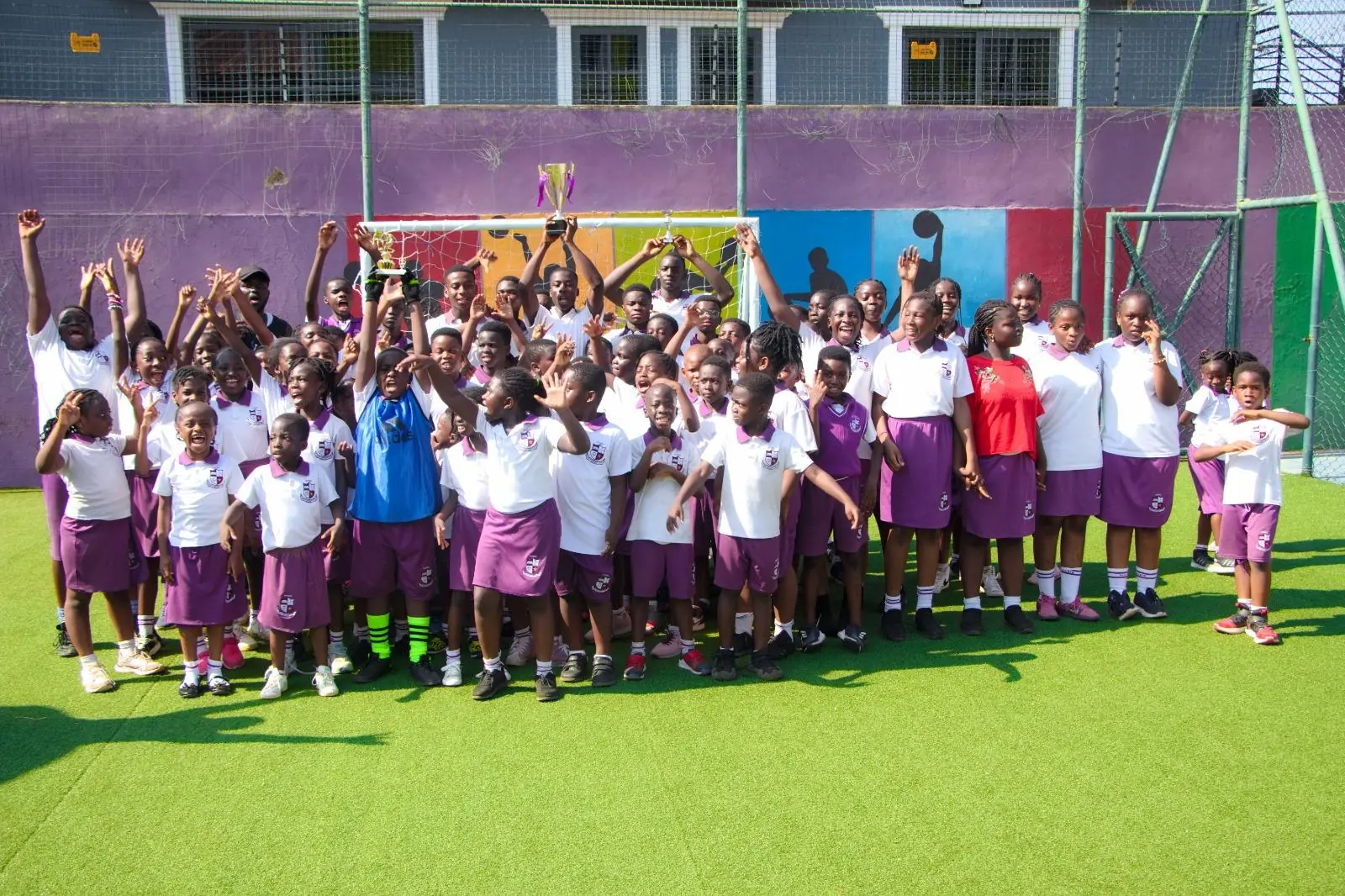 A group of HABIS pupils raising their hands together on the school court