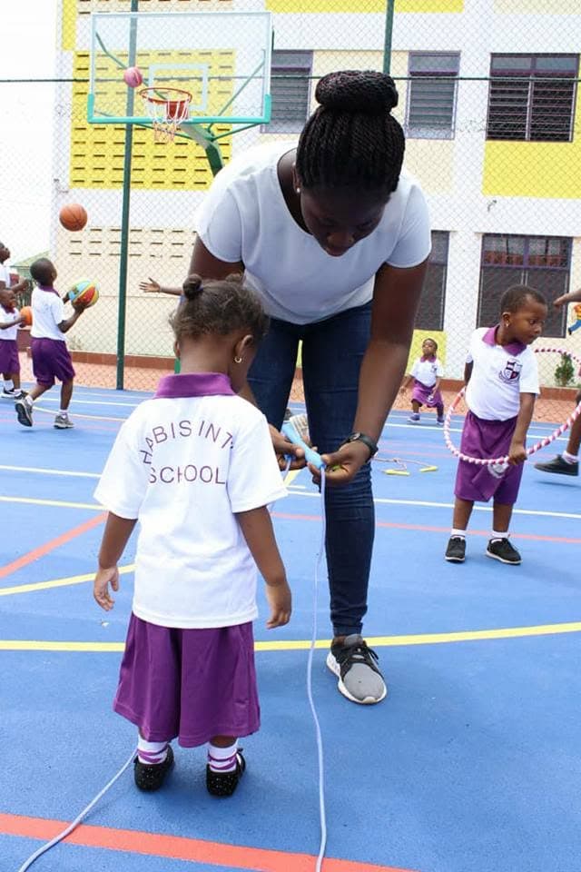 A teacher helping a pupil with skipping